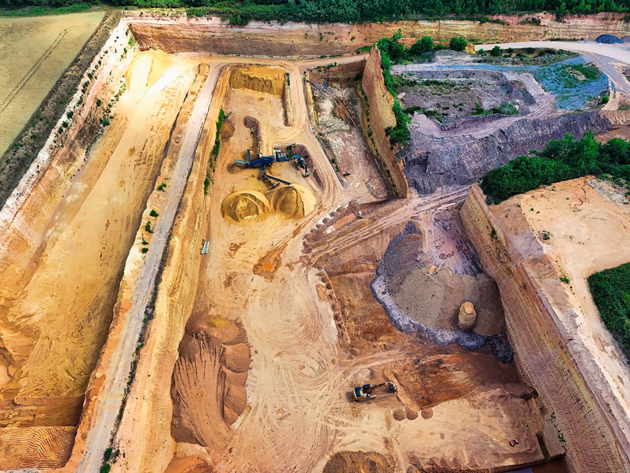 Aerial view of a large sandstone quarry with heavy machinery digging and piles of sand.